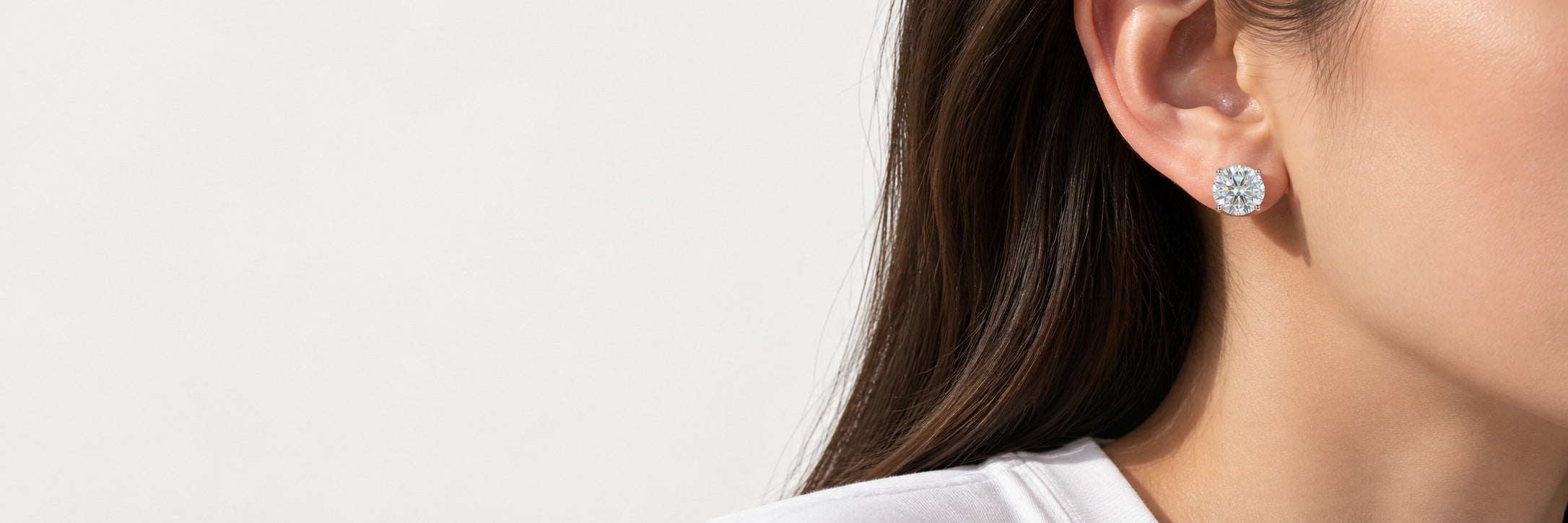 Close-up of a round stud earring worn with a white cotton shirt